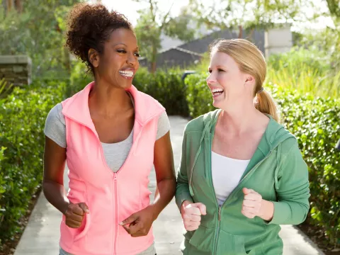 Two women discuss health on a walk outside.