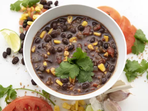 Bowl of tex-mex soup with tomato and green garnishes