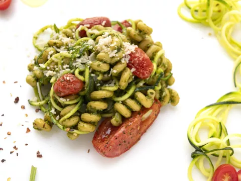 Mound of zucchini spiral pasta on white surface