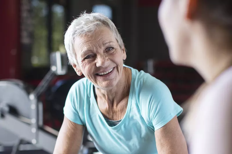 An older woman takes a break from working out on a rowing machine