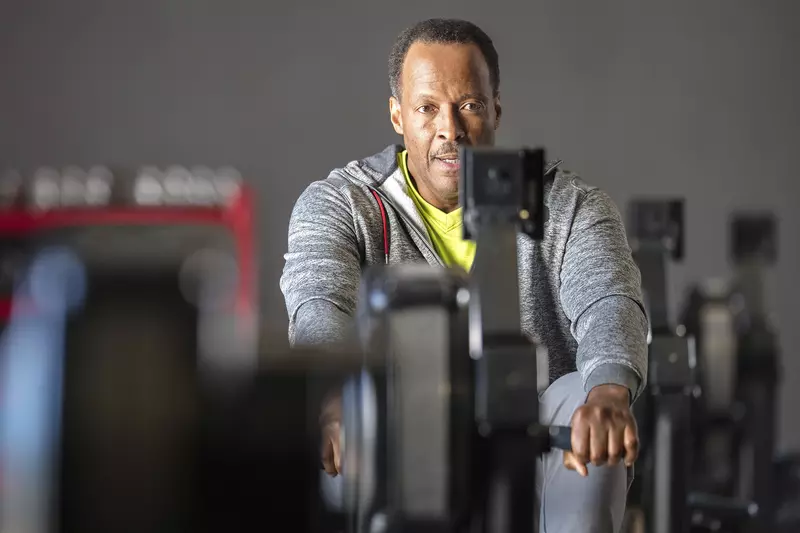An older African American man works out on a rowing machine at the gym.