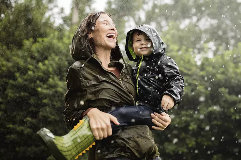 A mother and her young son play in the rain.