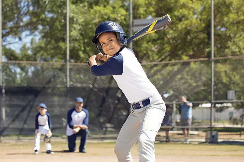 A young boy prepares to bat during an afternoon baseball game.