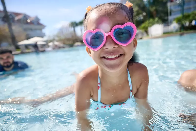 A Little Girl Swims in a Resort Pool Wearing Heart Shaped Goggles