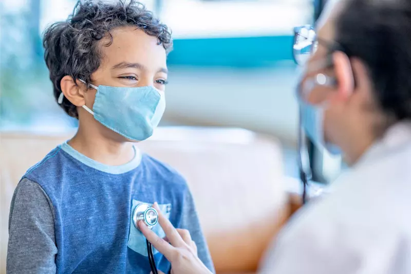 A doctor using her stethoscope on a youthful boy's chest