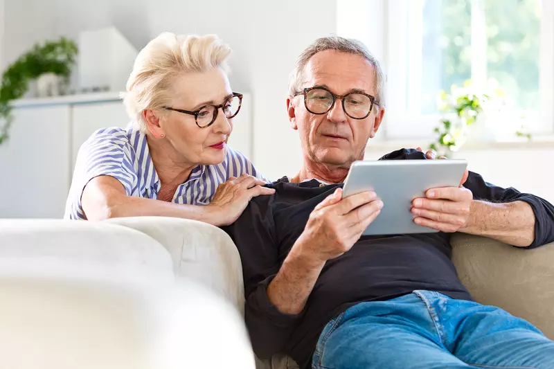 A Senior Couple Reads a Tablet Together in Their Home.