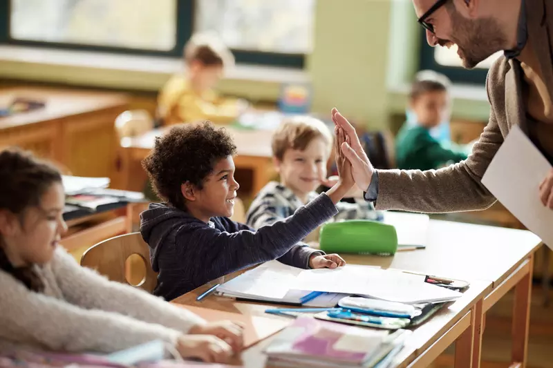 A Student High Fives His Teacher in the Classroom