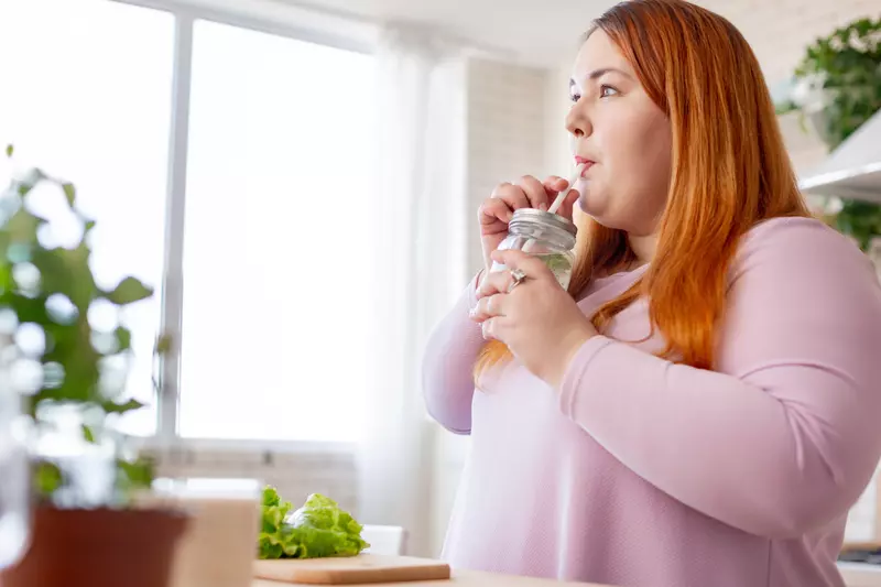 A Woman Drinks Infused Water In Her Kitchen