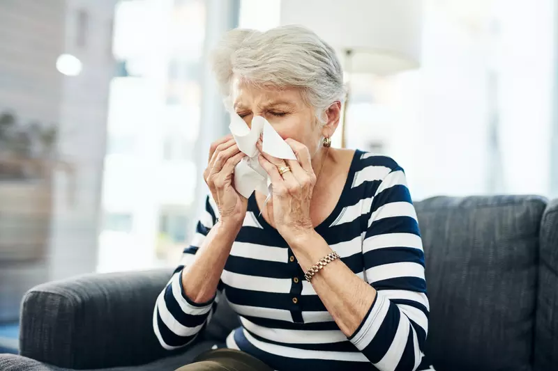 A Senior Woman Blow her Nose with a Tissue