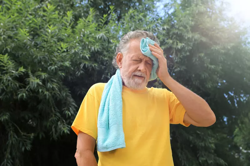 A Man Wipes the Sweat From His Forehead on a Hot Summer Day