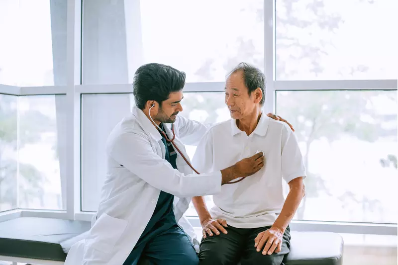A Physician Listens to His Patients Heart with a Stethoscope 