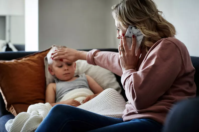 A Mother Checks Her Son's Temperature While on the Phone