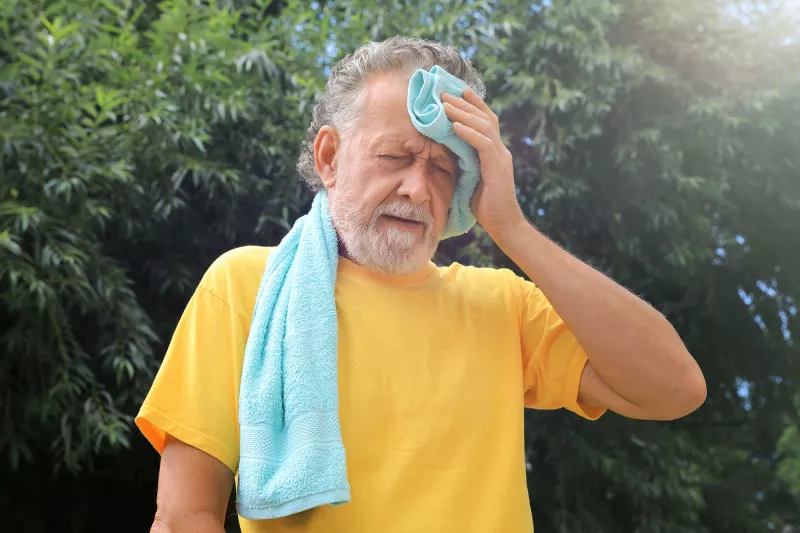 A Senior Wipes His Forehead While Out in the Hot Summer Sun 