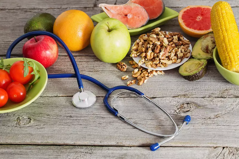 A wooden table with a spread of fruit and a stethoscope
