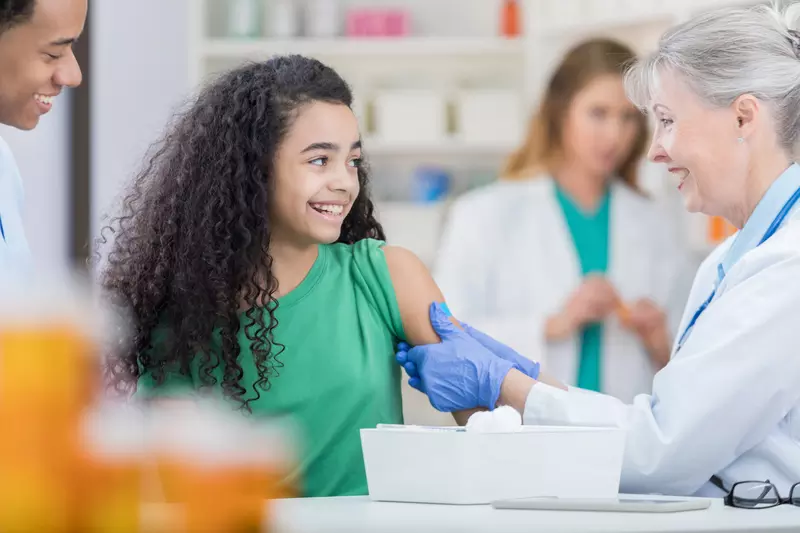 A preteen gets her first HPV vaccine shot from a nurse.