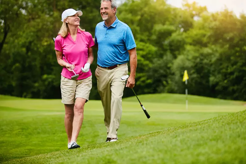 A senior couple, walking on a golf course.