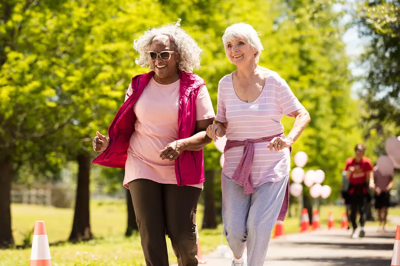 Two elderly women walking in the park.