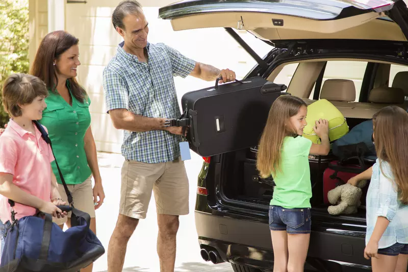 A family packs their car full of luggage.