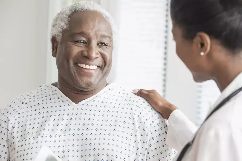 An older African American man receives consolation from a female physician.