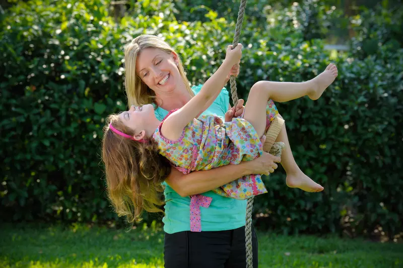 A mom helps her daughter swing. 