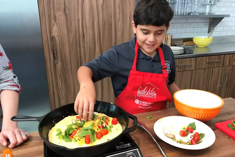 A boy cooks a fajita in a cast-iron pan.