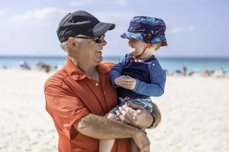 A grandfather and grandson practice sun safety at the beach.