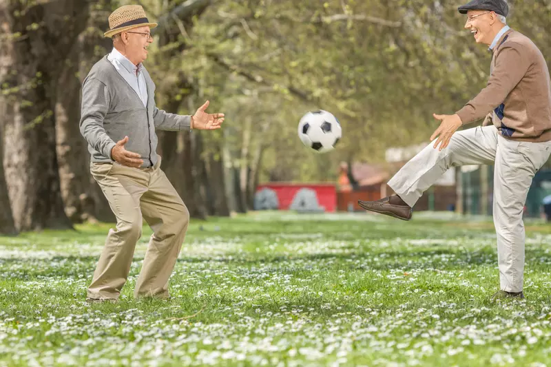 Seniors playing soccer in a park