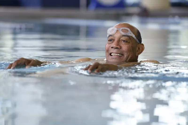 An African American man swims in an indoor pool for exercise