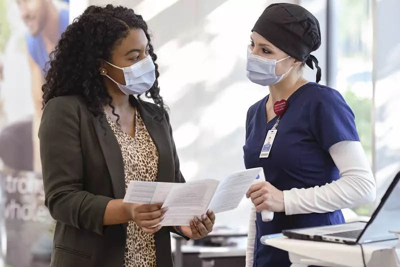 An AdventHealth employee assisting a patient with medical information