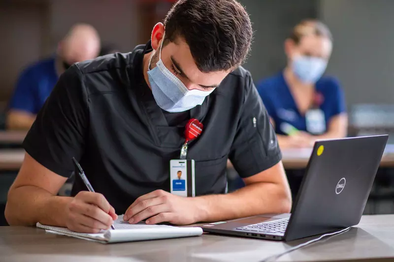 An AdventHealth nurse writing in his notepad