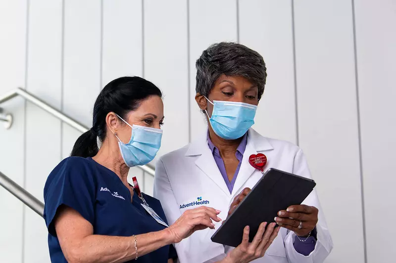 A AdventHealth nurse and physician in a discussion while holding a tablet.