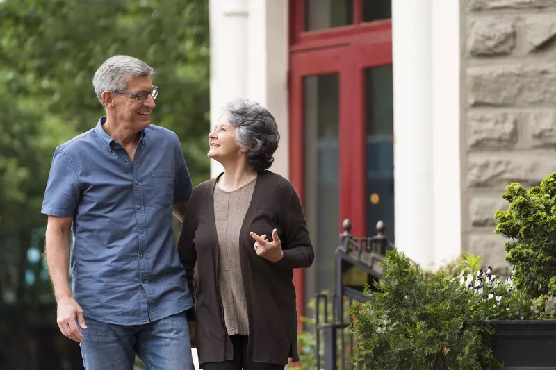 A senior man and woman walking outside of a building.