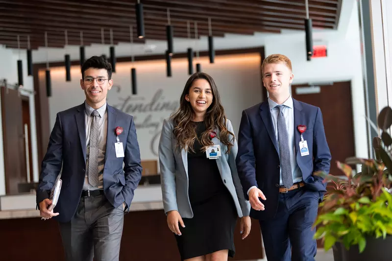 Three young professionals walking in the hallway of an office building