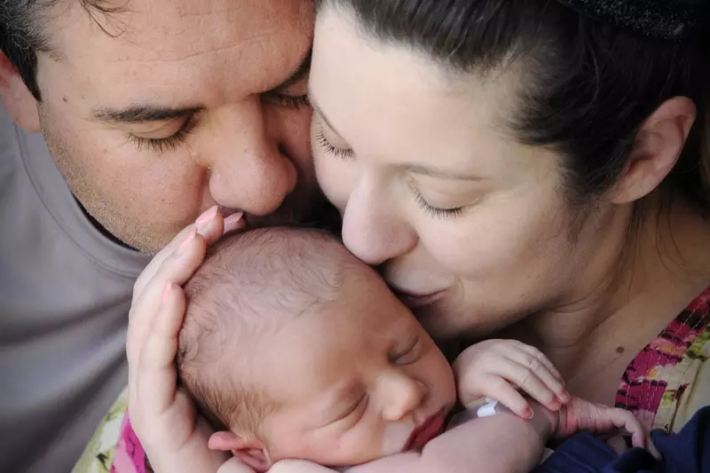 A couple holding and kissing their newborn baby.