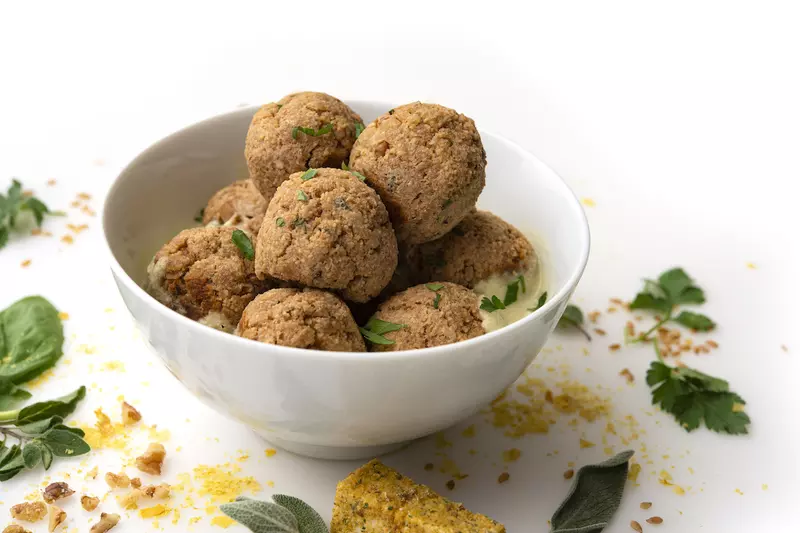 White bowl of no-meat balls with leaf garnishes on white counter
