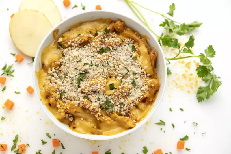 Bowl of mac and cheese with potato and parsley garnish