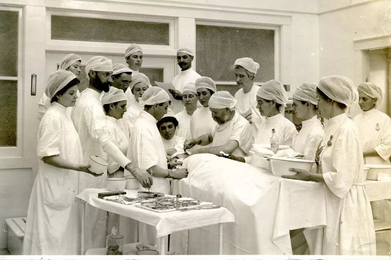 John Harvey Kellogg performing surgery with surgical team and viewers.