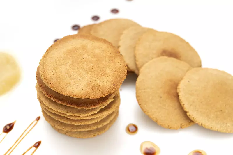 16 round, flat, golden cookies on a white surface
