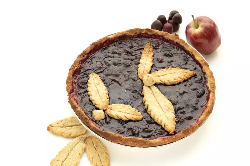 Whole cherry pie with apple, grapes, and leaf-piecrust garnishes