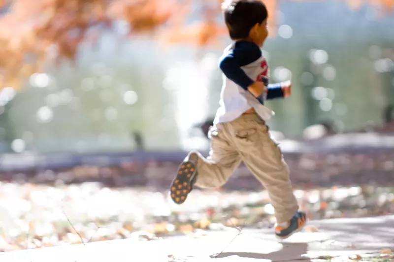 A small boy runs beneath the autumn leaves