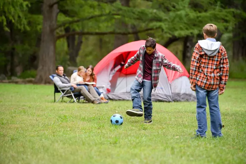 Two boys play soccer on a family camping trip