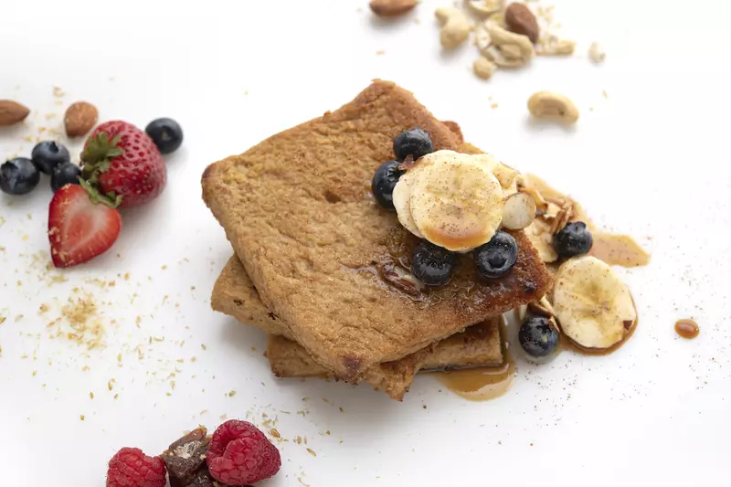 Three stacked slices of French toast with banana and berry garnishes