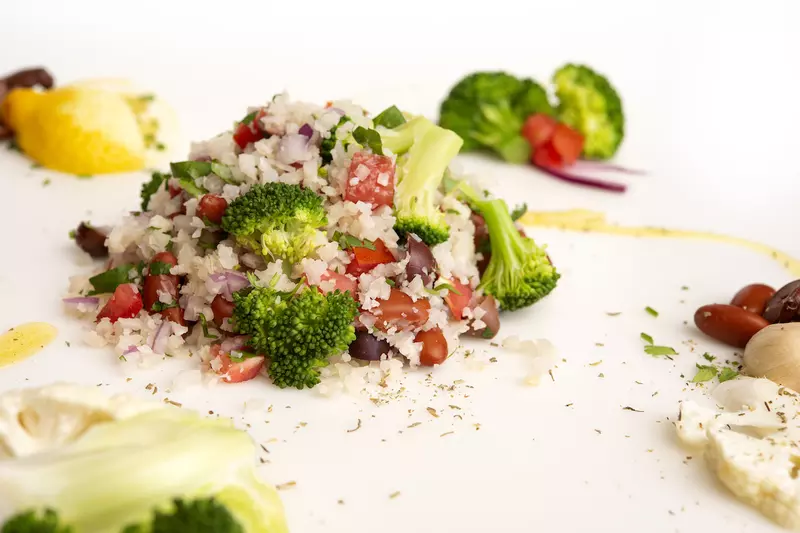 Mound of cauliflower rice salad with lemon and broccoli garnishes