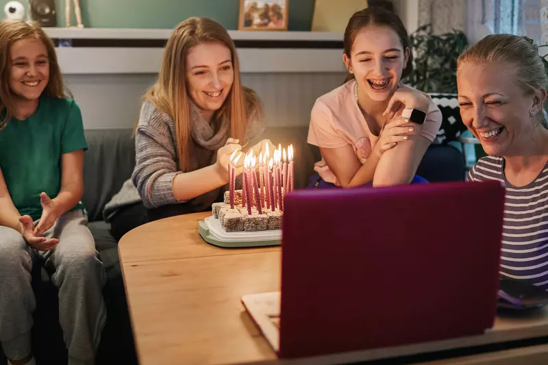 A family celebrating a birthday over video chat. 
