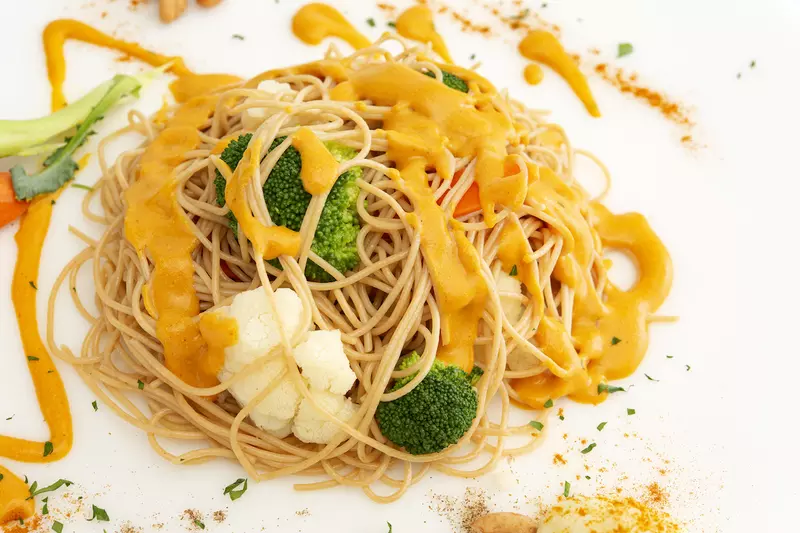 Mound of cheesy vegetable pasta on white surface