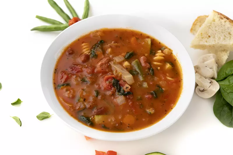 Bowl of minestrone soup with garnishes