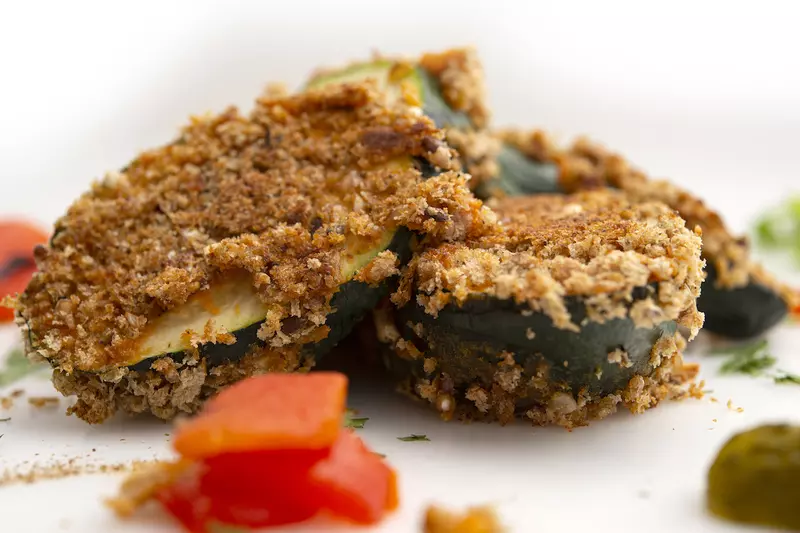 Three crusted zucchini fritters with tomato garnishes