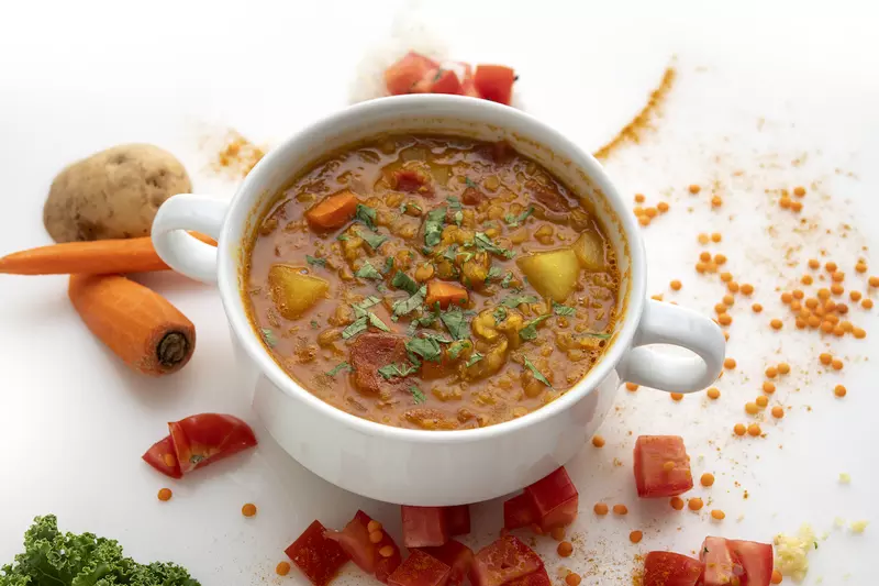 Bowl of lentil soup with carrot garnishes