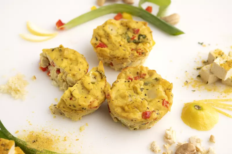 Three eggless frittatas on white surface with green onion garnish