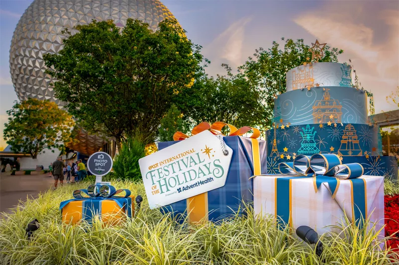 Epcot International Festival of the Holidays sign and presents with Spaceship Earth in the background.